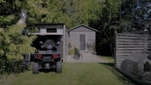 A garage with a vehicle and a small shed. - Cozy Bunkie by a Tranquil Freshwater Pond in Clarington, Ontario (Bowmanville)