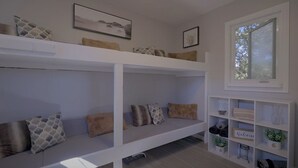 A room with bunk beds, a white shelving unit with decorative items, and a window with a view. - Cozy Bunkie by a Tranquil Freshwater Pond in Clarington, Ontario (Bowmanville)