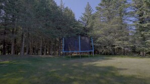 A fenced area surrounded by tall trees. - Cozy Bunkie by a Tranquil Freshwater Pond in Clarington, Ontario (Bowmanville)