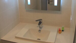 Une salle de bain avec un lavabo blanc, un miroir au-dessus et un meuble en bois en dessous.