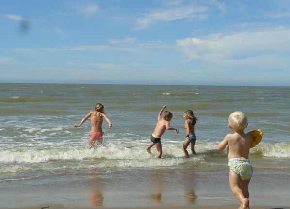 Een strandscène met kinderen die in het water spelen.
