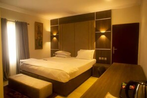 Une chambre d’hôtel avec un lit, un bureau et une porte.