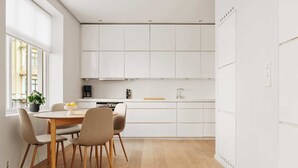 Eine moderne Küche mit weißen Schränken, einem Holztisch und Stühlen.