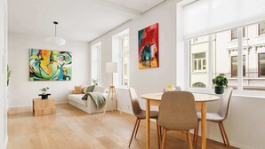 Ein modernes Wohnzimmer mit Essbereich, Holzböden, weißen Wänden und großen Fenstern.