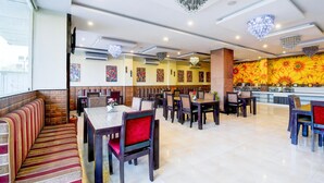 A restaurant with booths, tables, and chairs, featuring a colorful wall mural and chandeliers. - Luxury Stays With Pool Near Akshardham Temple (Jaipur)