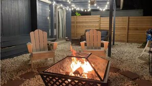 Un brasero rodeado de grava y una terraza de madera, con dos sillas Adirondack.