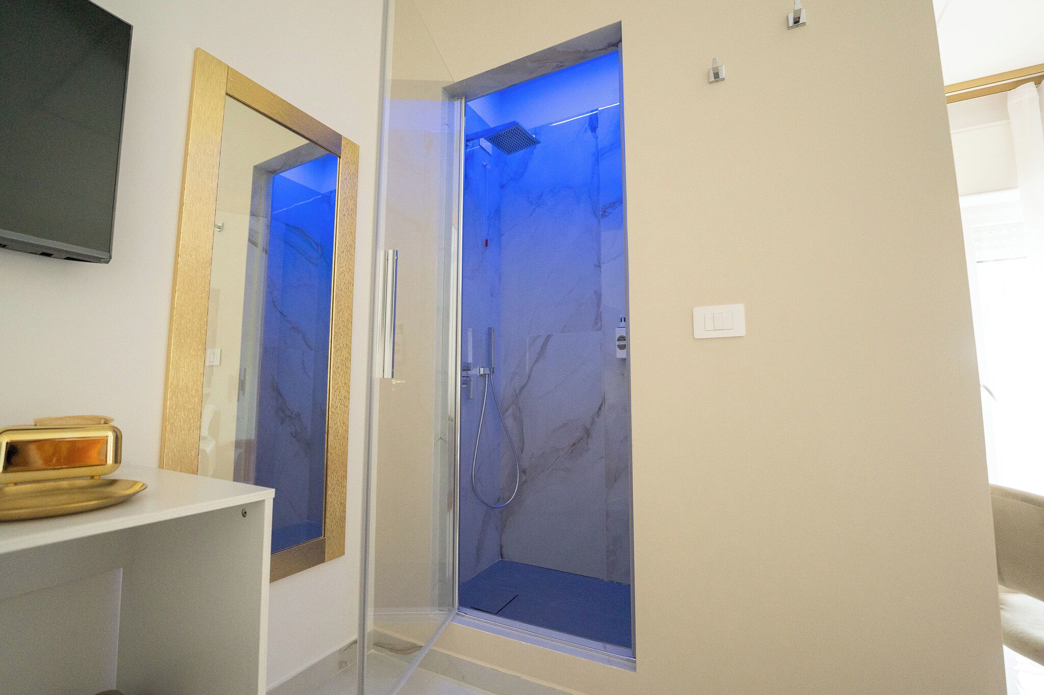A modern bathroom with a glass-enclosed shower, a wooden-framed mirror, and a white countertop.