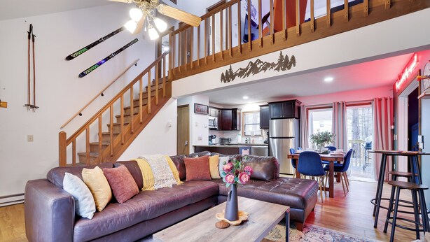 Una sala de estar moderna con un sofá de cuero, una mesa de centro de madera y una escalera que sube a un nivel superior.