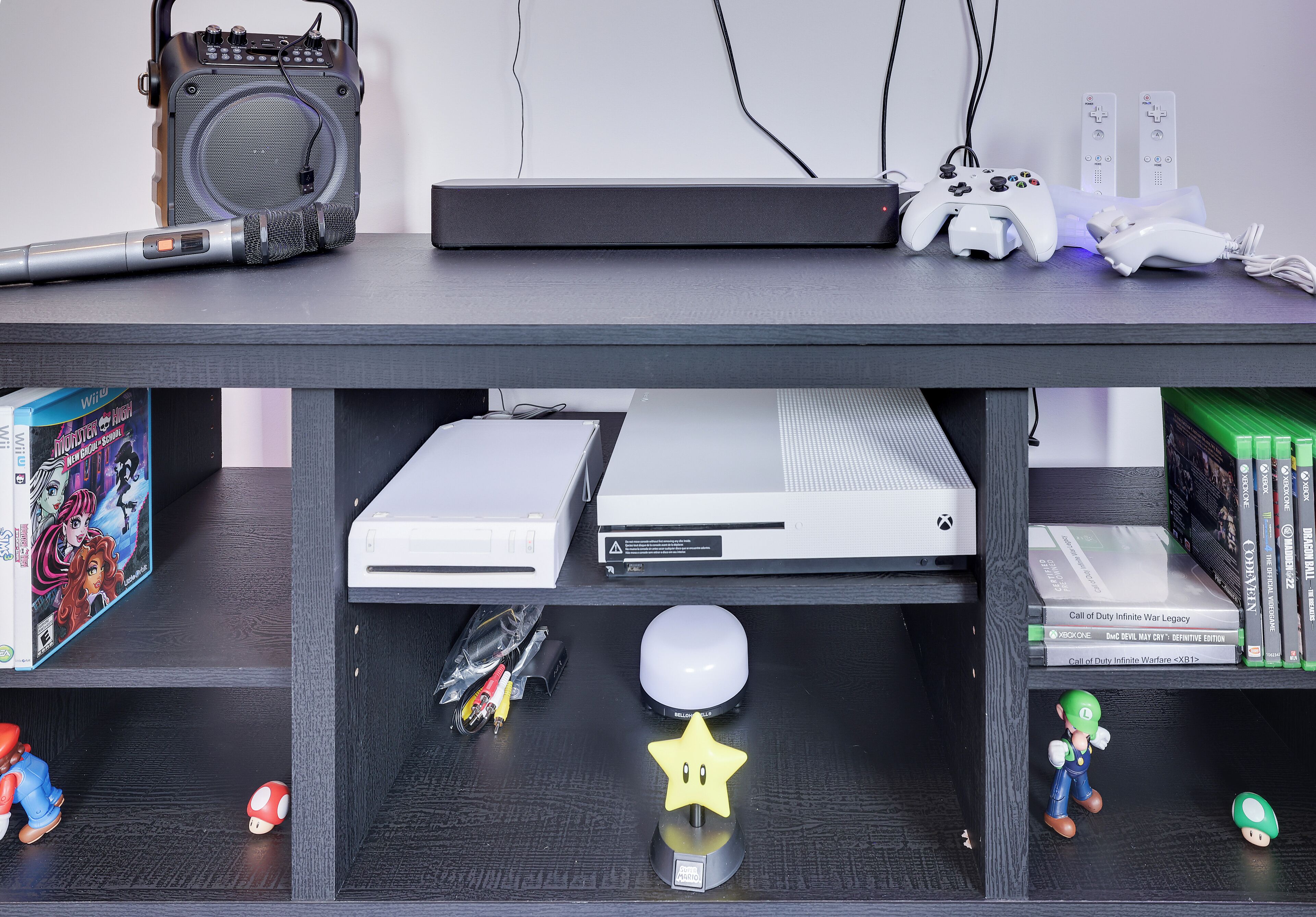 Ein Gaming-Setup mit Konsole, Controllern und Lautsprecher.