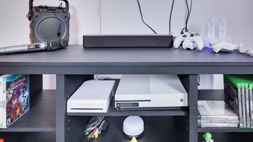 Ein Gaming-Setup mit Konsole, Controllern und Lautsprecher.