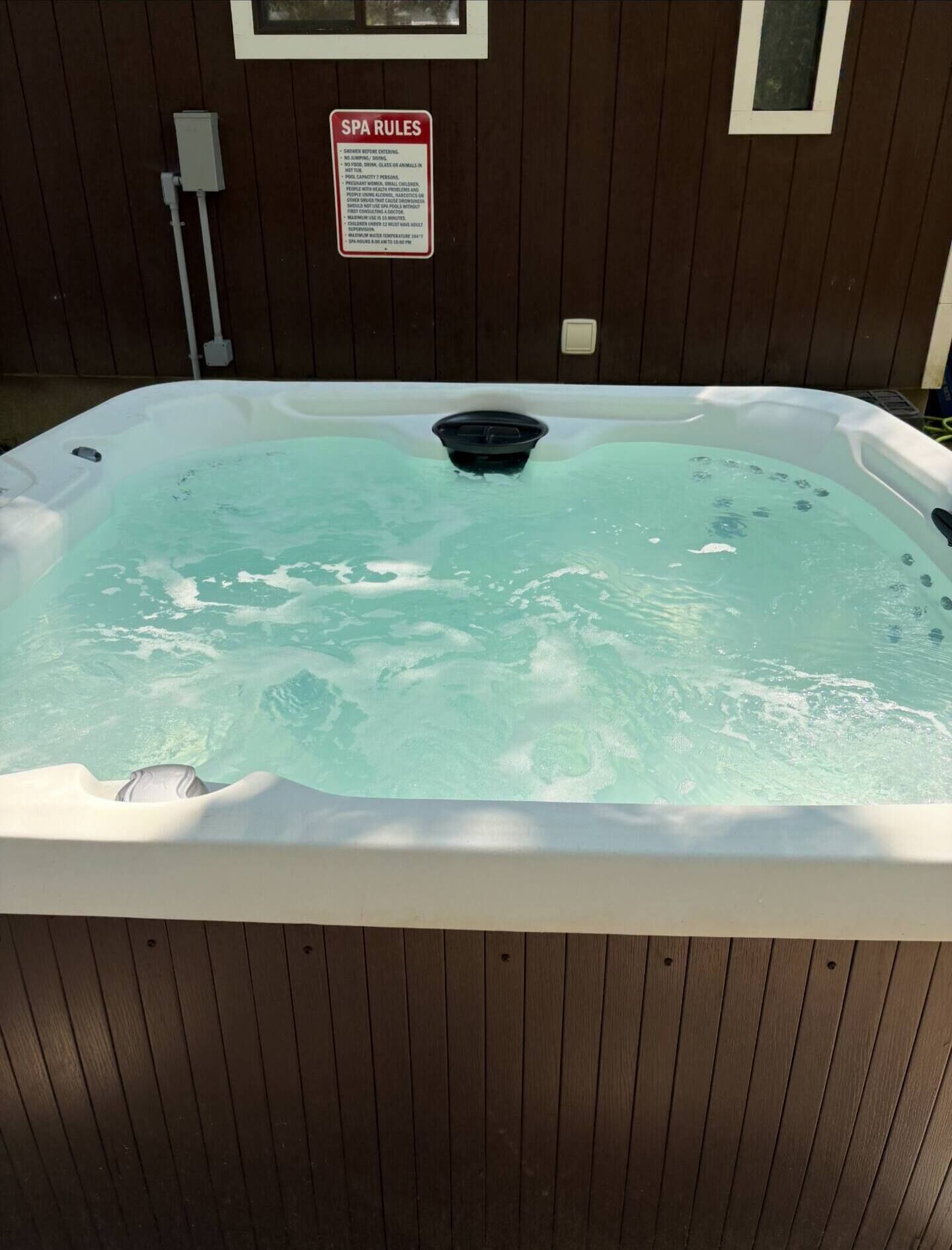 Een whirlpool met een bord erboven waarop 'SPA REGELS' staat.