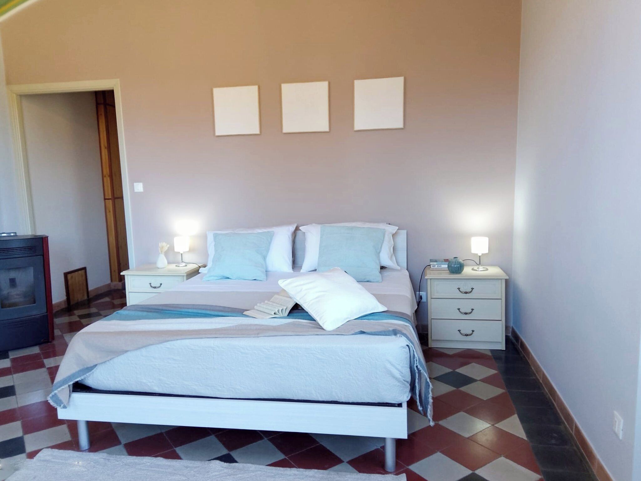 A bedroom with a bed, two bedside tables, a nightstand, a dresser, and a door.