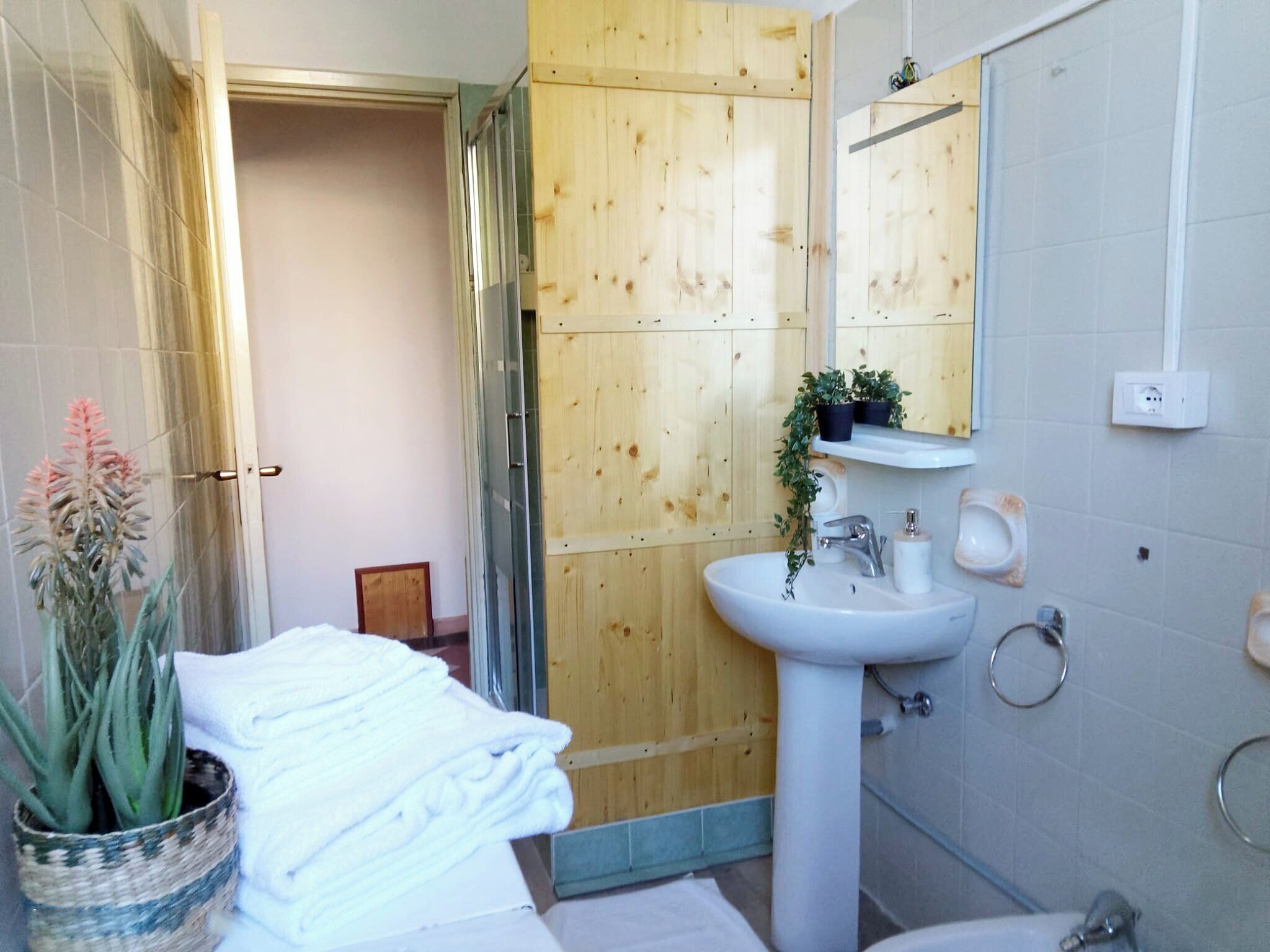 Une salle de bain avec un mur en bois, un lavabo blanc, un miroir et des toilettes.
