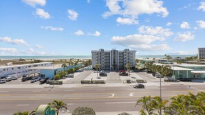 A multi-story hotel with a parking lot in front, a beach view, and palm trees. - Upscale Comfort with and Affordable Price 🏝 Beach Access across the street (Treasure Island)