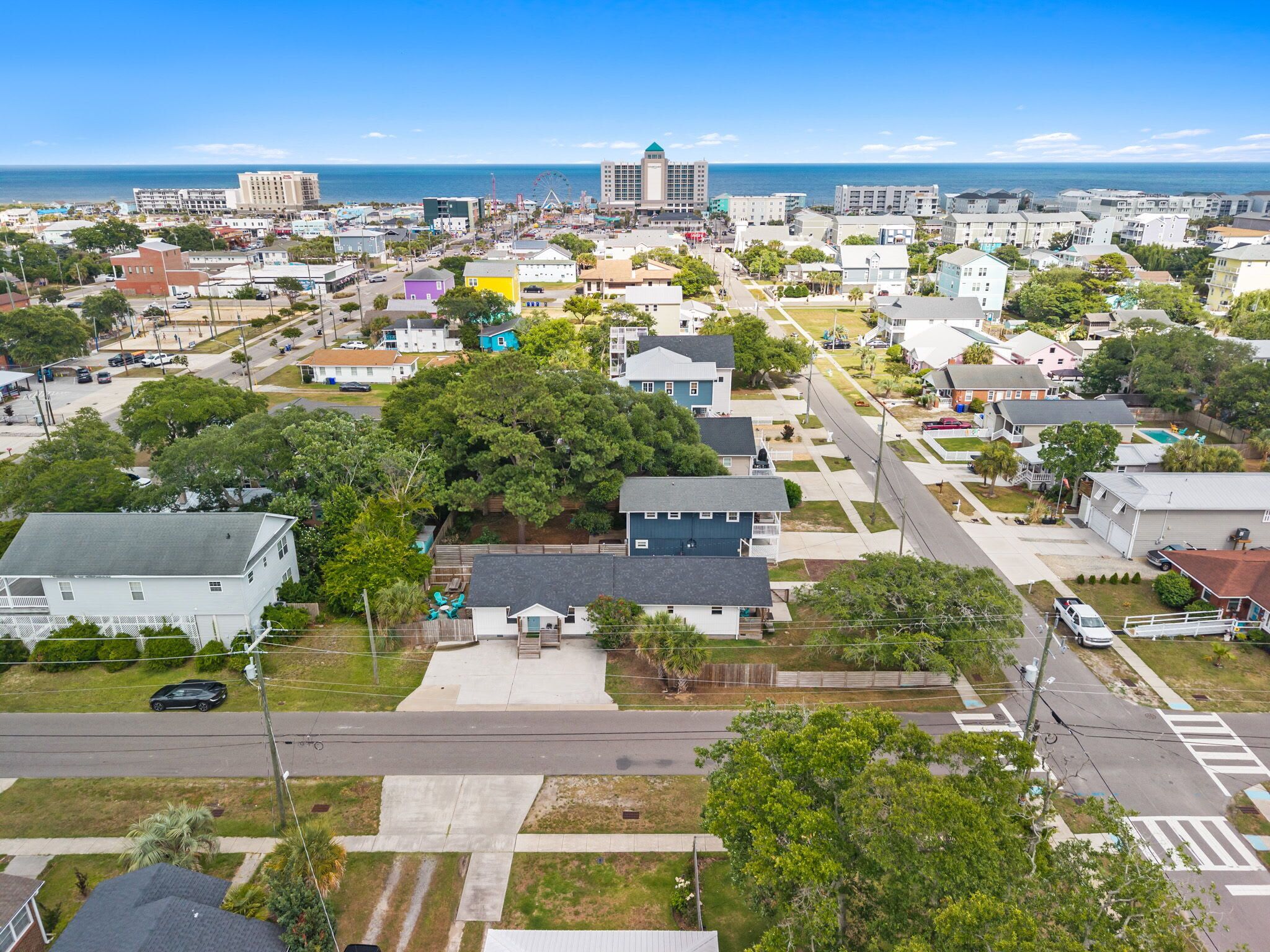 An aerial view of a coastal town with residential buildings, a prominent building with a dome, and a clear view of the ocean.
