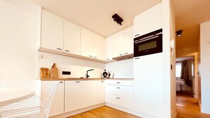 A modern kitchen with white cabinets, a wooden countertop, and a built-in oven. - Apartment in Wenduine Near Zeedijk Beach (De Haan)