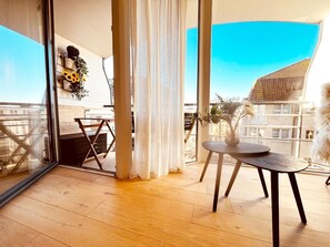 A modern balcony with wooden flooring, a round table, and a chair. - Apartment in Wenduine Near Zeedijk Beach (De Haan)