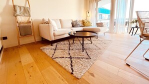 A modern living room with a sofa, coffee table, and a wooden floor. - Apartment in Wenduine Near Zeedijk Beach (De Haan)