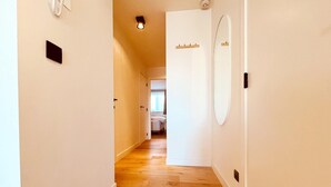 A hallway with wooden flooring, a white door with a mirror, and a light fixture on the ceiling. - Apartment in Wenduine Near Zeedijk Beach (De Haan)