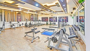 Une salle de sport équipée de divers appareils d’exercice, de miroirs et dotée d’un plancher en bois.