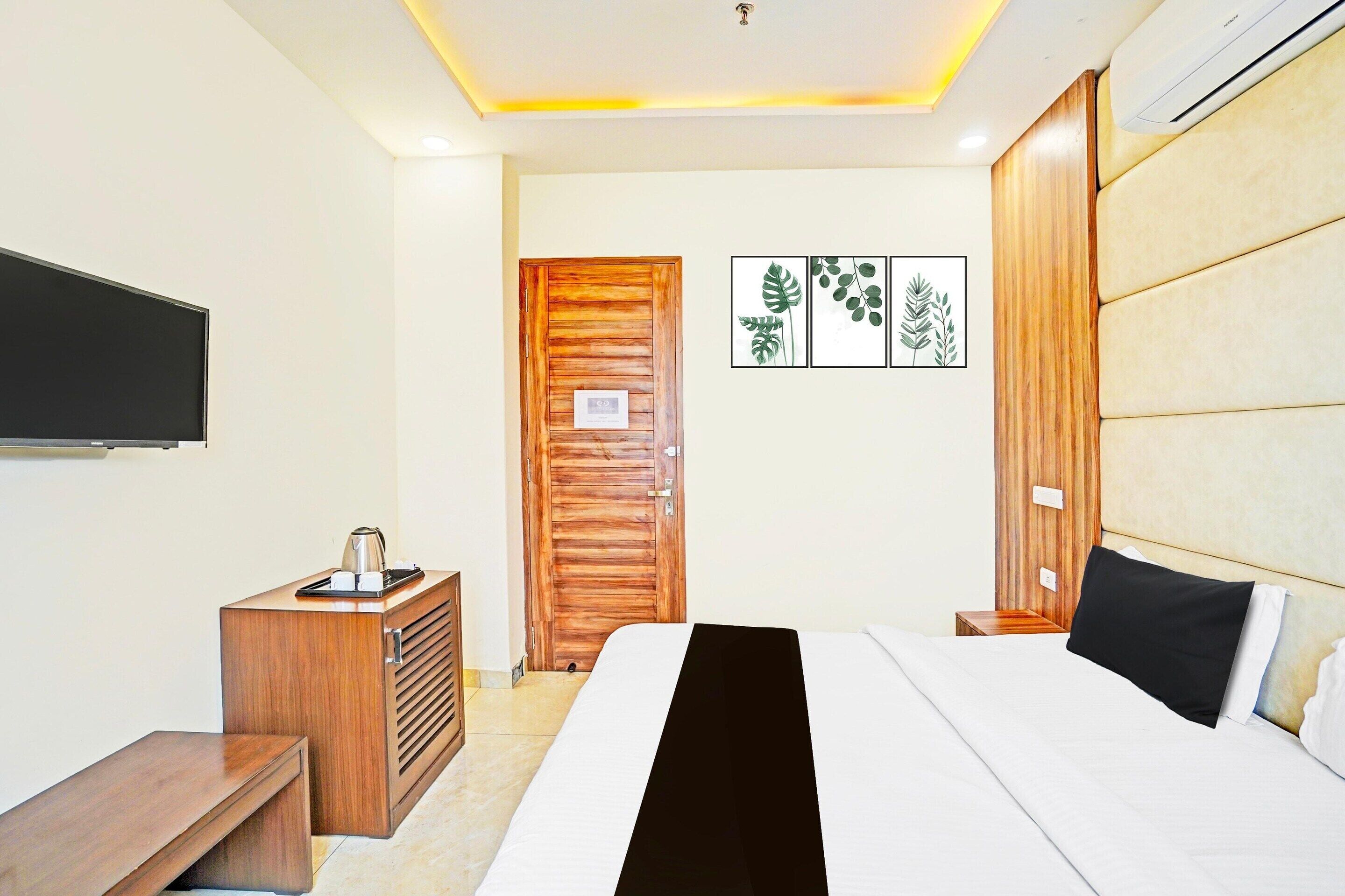 A hotel room with a bed, a wooden dresser, a television, and wall art.