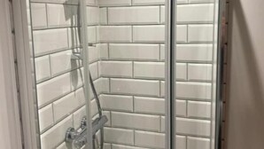 A glass-enclosed shower with white tiled walls and a chrome showerhead. - Maypole Farm Guest House (Selby)