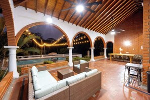 Un patio exterior con mobiliario, piscina y techos abovedados.