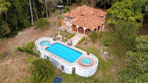 Una piscina amplia con un jacuzzi circular, rodeada por un solárium blanco.
