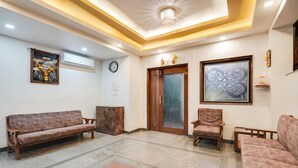 A spacious lobby with a marble floor, two sofas, a wooden cabinet, and a door with glass panels. - Elegant Escape in Palette Bhimpore Daman (Daman)