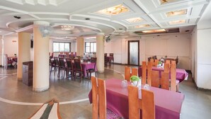 A spacious dining area with round tables and chairs, large pillars, and a modern ceiling design. - Elegant Escape in Palette Bhimpore Daman (Daman)