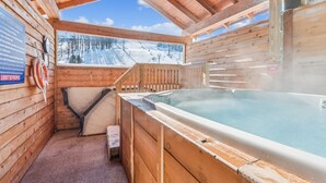 A wooden cabin with a hot tub, a view of a snowy mountain, and a sign indicating an emergency stop. - ❄ The Snowballer – Ultimate Ski-In/Ski-Out Retreat! 🎿🏔 (Champion)