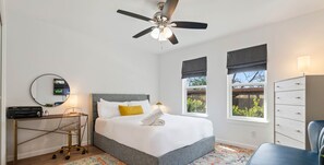 Relax in a cozy space with a neatly made bed, desk, and comfortable chair.