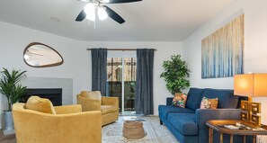 Relax in this stylish living room with a large sofa, colorful throw pillows, and a unique abstract painting.