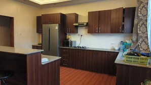 Una cocina moderna con armarios de madera oscura, un refrigerador de acero inoxidable, un microondas y una estufa a gas.