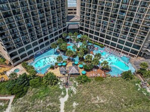 A high-rise hotel with multiple balconies, a central swimming pool area with palm trees, and a rooftop bar. - Beachfront Haven | Ocean Views & Pool | Sleeps 4 (North Myrtle Beach)