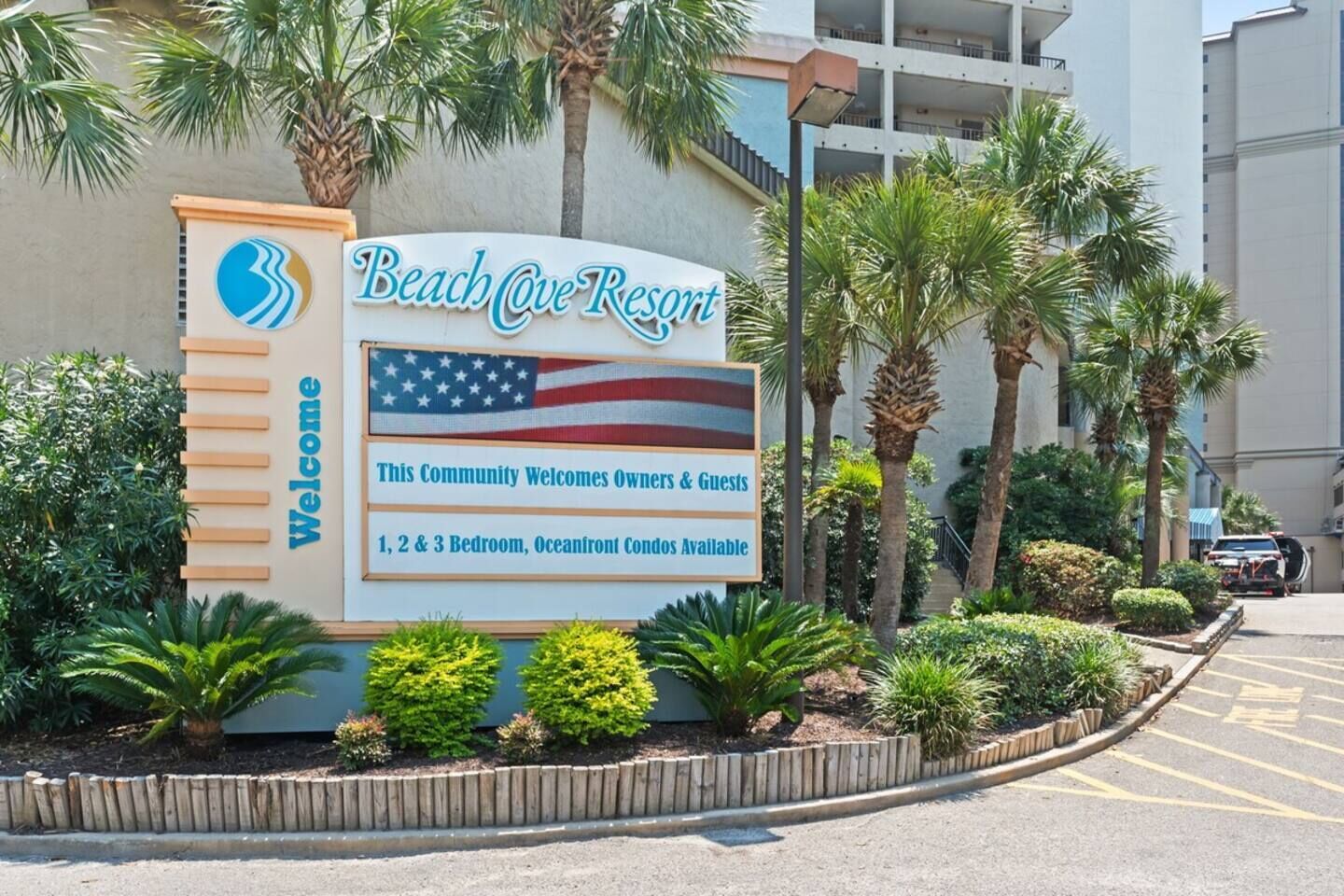 A sign for Beach Cove Resort welcoming guests and indicating available 1, 2, and 3 bedroom oceanfront condos.