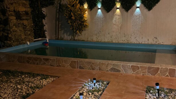 A pool area with a stone pathway, decorative lighting, and a wall with geometric patterns. - IDEAL HOUSE TO REST, SWIMMING POOL, BBQ, WIFI, FULL AIRE (Sabanilla)