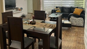 A modern living room with a dining area, featuring a TV, a sofa, and a coffee table. - IDEAL HOUSE TO REST, SWIMMING POOL, BBQ, WIFI, FULL AIRE (Sabanilla)