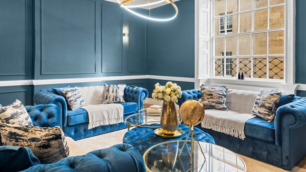 Una habitació amb sofàs tapissats de blau, una taula de centre de vidre i un globus decoratiu.