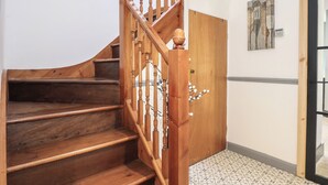 A wooden staircase with a handrail, a door, and a patterned floor.