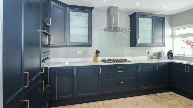 A modern kitchen with dark cabinetry, a stainless steel range hood, and a window providing natural light.