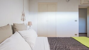 A bedroom with a bed, a hanging light fixture, a door, and an air conditioning unit. - Central Rome Terrace Apartment (Roma)