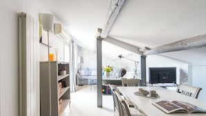 A modern, well-lit dining area with a white table, chairs, and a bookshelf filled with books and decorative items. - Central Rome Terrace Apartment (Roma)