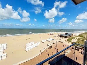 A beach with white tents and a building, a clear sky, and the ocean. - Apartment in Wenduine With Sea Views (De Haan)