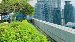 En taghave med grønne planter og udsigt til Petronas Twin Towers.