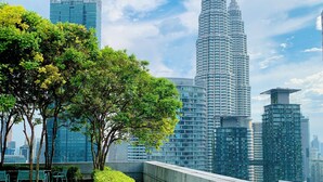 Taghave med siddepladser, udsigt til Petronas Towers og en bysilhuet i baggrunden.