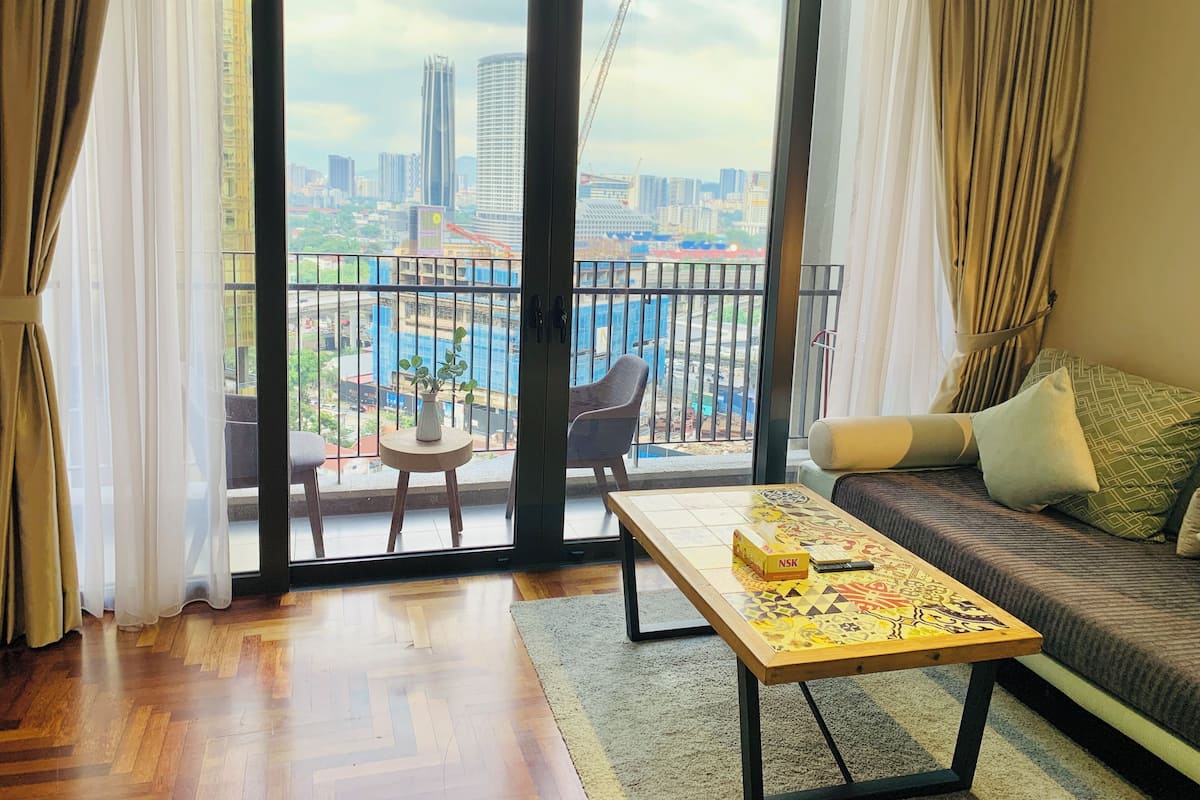 A living room with a sofa, a coffee table, and a view of a cityscape through a large sliding glass door.