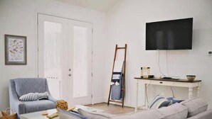 Olohuoneessa on sohva, nojatuoli, sohvapöytä, televisio ja tikkaat.