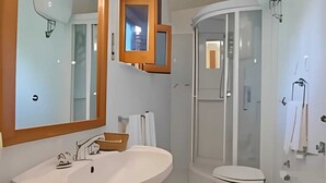 Et moderne badeværelse med et stort spejl, vask, toilet og brusebad.