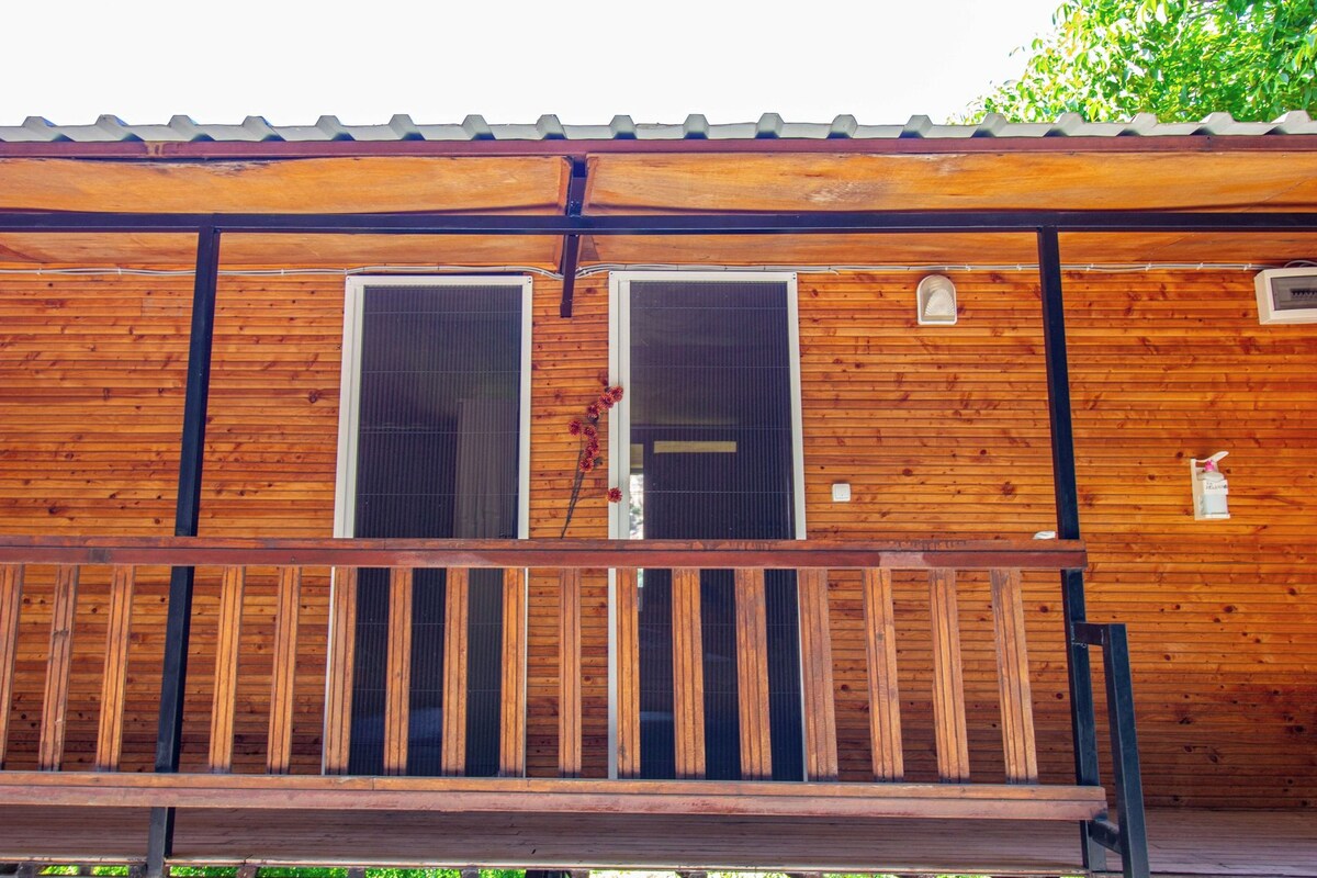 A wooden cabin with a balcony and two large windows.